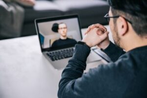 Hispanic male therapist conducts talk therapy session online with a white male patient